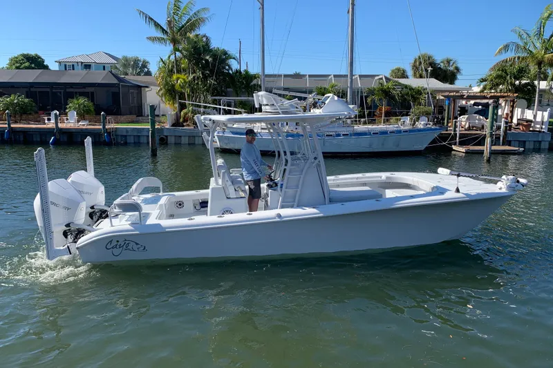 Slide: The Image of 2021 Costa Custom Boats 264HC cruising in a sunny marina, showcasing sleek design and powerful engines. - 2