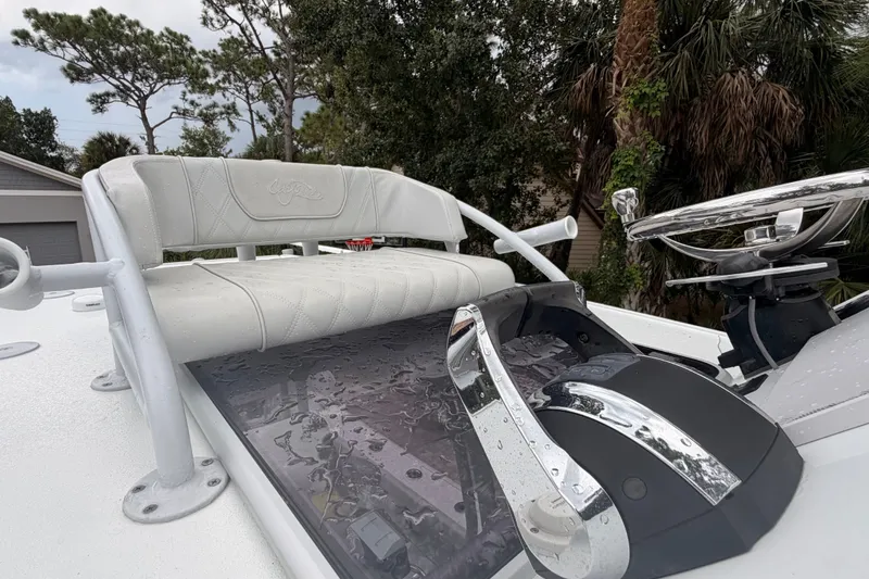 Slide: The Image of 2021 Costa Custom Boats 264HC helm with white seating and chrome controls, surrounded by trees. - 12