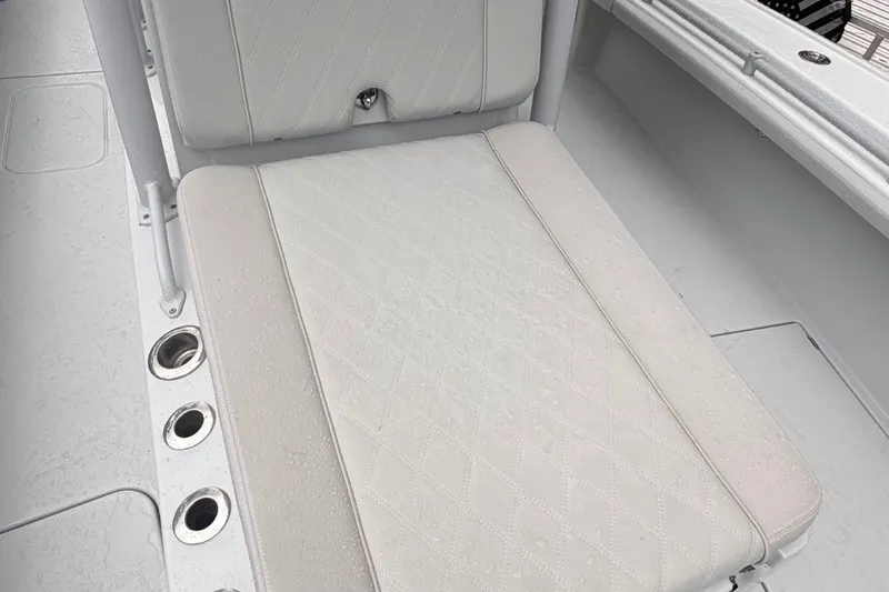 Slide: The Image of White cushioned seating on 2021 Costa Custom Boats 264HC, featuring diamond pattern and cup holders. - 20