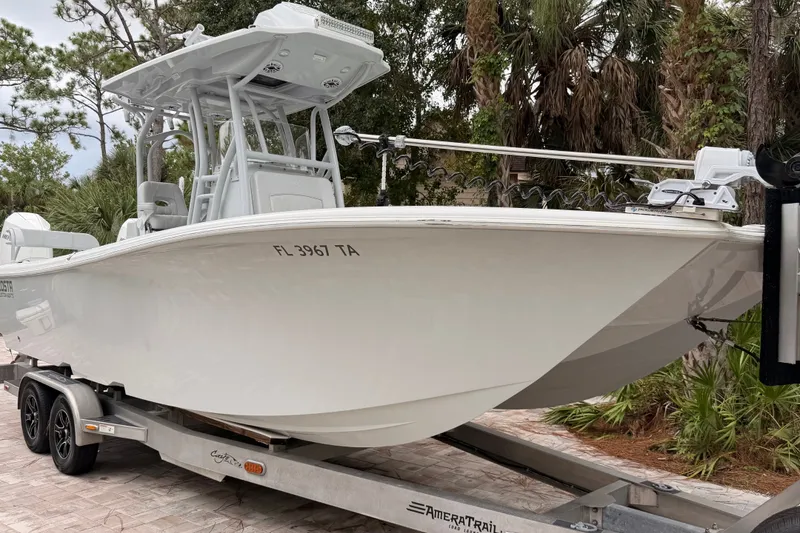 Slide: The Image of 2021 Costa Custom Boats 264HC on trailer, surrounded by trees. - 4