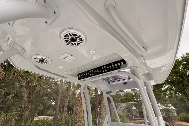 Slide: The Image of 2021 Costa Custom Boats 264HC T-top with speakers and control panel, surrounded by trees. - 30