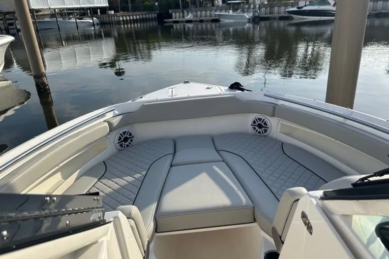 Slide: The Image of 2025 Pursuit DC 266 Dual Console boat interior with cushioned seating at a marina. - 11