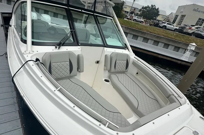 Slide: The Image of 2025 Pursuit DC 266 Dual Console boat with luxurious seating at a marina dock. - 9