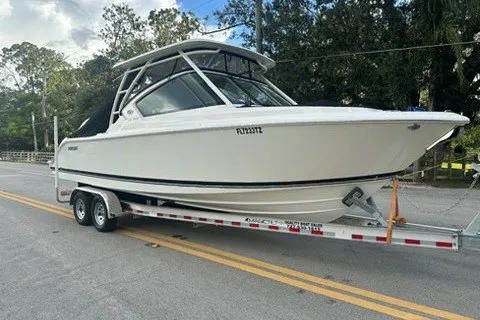 Slide: The Image of 2025 Pursuit DC 266 Dual Console boat on trailer, parked on a road. - 0