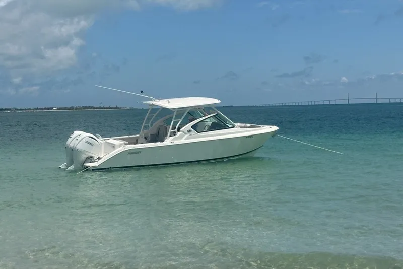 Slide: The Image of 2025 Pursuit DC 266 Dual Console boat anchored in clear blue water. - 2