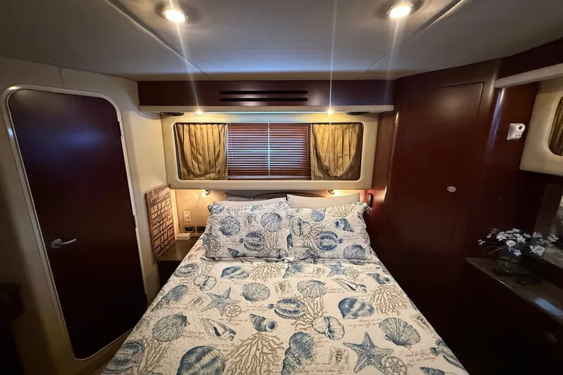 Slide: The Image of Luxurious 2007 Sea Ray 40 Motor Yacht bedroom with nautical-themed bedding and elegant wood finishes. - 83