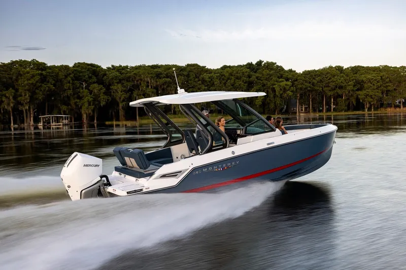 The Image of 2027 Monterey Elite 25 OB boat cruising on a serene lake with lush greenery. - 20