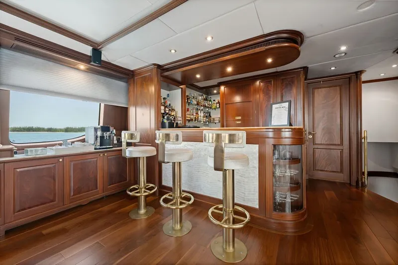 Slide: The Image of Luxurious wooden bar interior on 2007 Benetti 120 Classic yacht with elegant stools and stocked shelves. - 87
