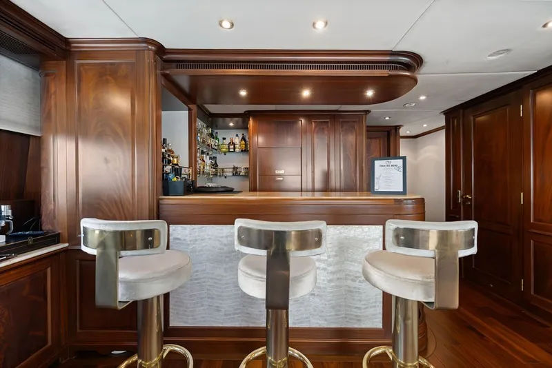 Slide: The Image of Luxurious yacht bar interior on a 2007 Benetti 120 Classic, featuring elegant wood paneling and modern stools. - 88