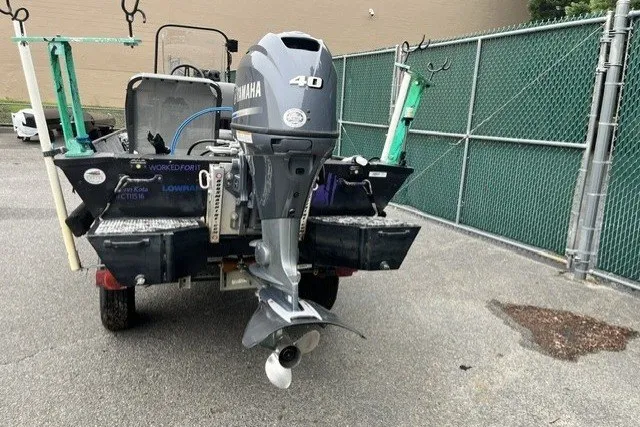 Slide: The Image of 1995 Lowe L1648 Jon boat with Yamaha 40 outboard motor, parked near a chain-link fence. - 5