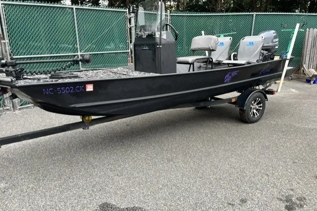 Slide: The Image of 1995 Lowe L1648 Jon boat on trailer, parked near green fence. - 2