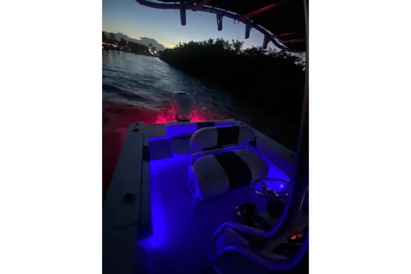 Slide: The Image of 2018 Robalo R202 Explorer boat with blue interior lights at dusk on the water. - 4
