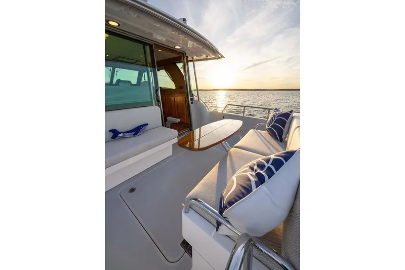 Slide: The Image of Manufacturer Provided Image: Luxurious 2027 Sabre 38 Salon Express yacht deck at sunset, featuring elegant seating and cushions. - 6