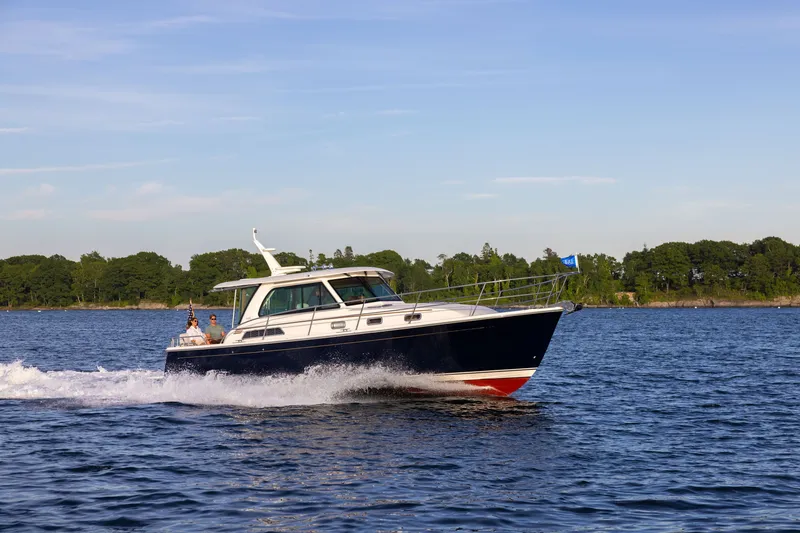 Slide: The Image of 2027 Sabre 38 Salon Express cruising on a serene lake under a clear blue sky. - 2