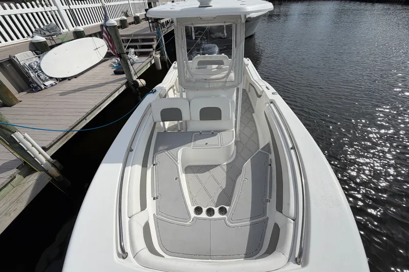 Slide: The Image of 2014 Tidewater 230 LXF boat docked, showcasing spacious deck and seating area. - 15