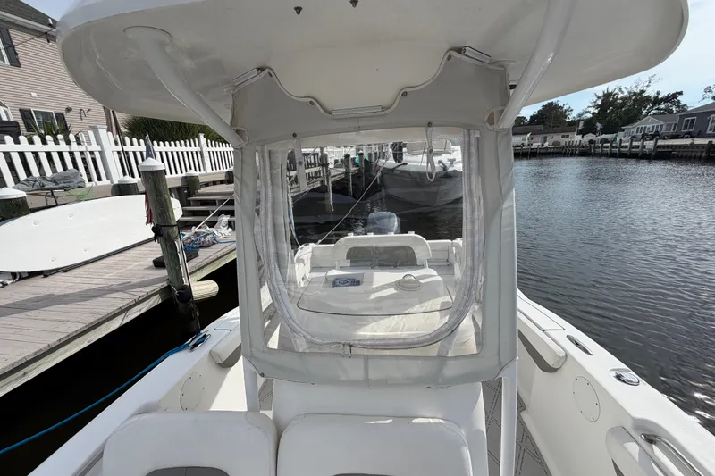 Slide: The Image of 2014 Tidewater 230 LXF boat docked by a waterfront, featuring a clear enclosure. - 18