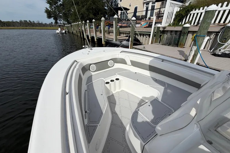 Slide: The Image of 2014 Tidewater 230 LXF boat docked by a waterfront home, showcasing spacious deck and seating. - 14
