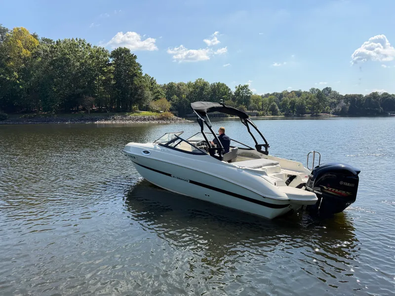 Slide: The Image of A white motorboat floating on a calm lake, surrounded by trees. - 2