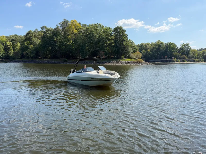 Slide: The Image of A 2021 Stingray 214 LR cruising on a calm lake with a wooded shoreline. - 8