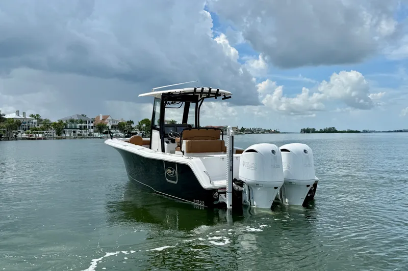 Slide: The Image of 2021 Sea Hunt Gamefish 27FS boat with dual engines on calm water under cloudy sky. - 24