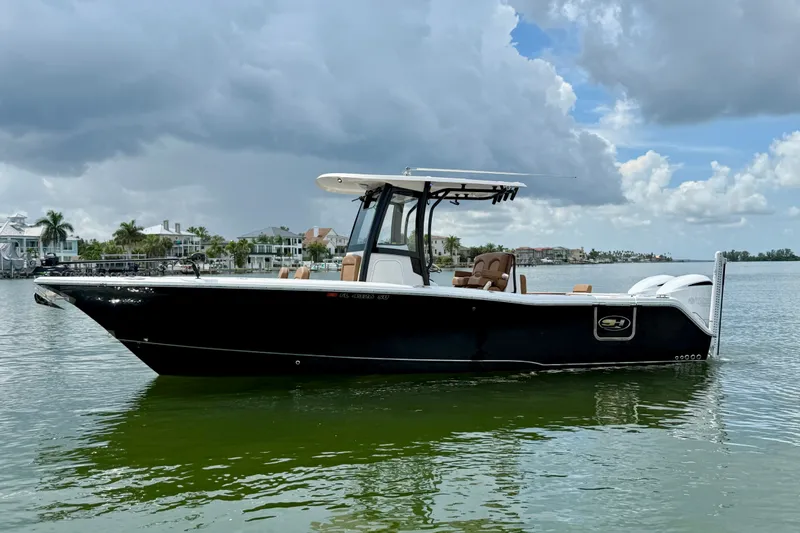 The Image of 2021 Sea Hunt Gamefish 27FS boat on calm water under cloudy sky. - 0