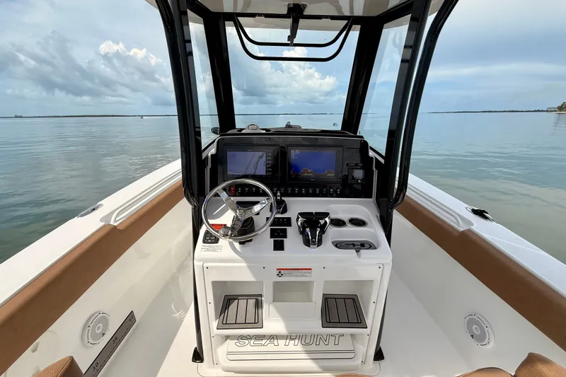 Slide: The Image of 2021 Sea Hunt Gamefish 27FS boat console with navigation screens on calm water. - 7