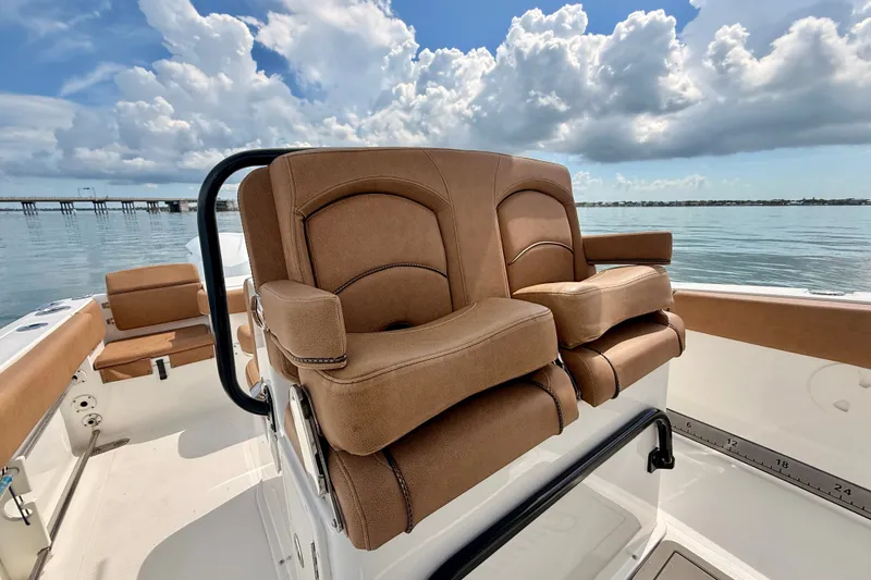 Slide: The Image of 2021 Sea Hunt Gamefish 27FS boat interior with brown seating, ocean view, and cloudy sky. - 11