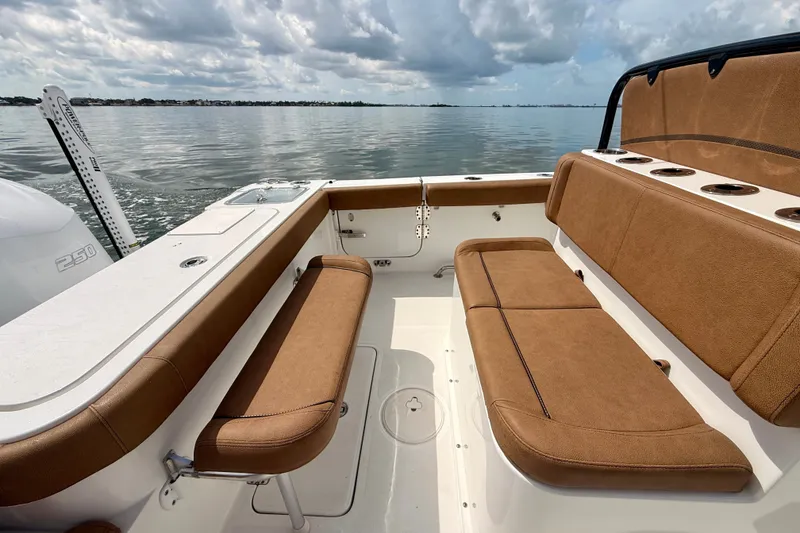 Slide: The Image of 2021 Sea Hunt Gamefish 27FS boat interior with brown seating, calm water backdrop. - 16