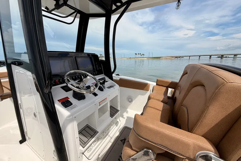 Slide: The Image of 2021 Sea Hunt Gamefish 27FS boat interior with helm and seating, overlooking calm waters. - 6