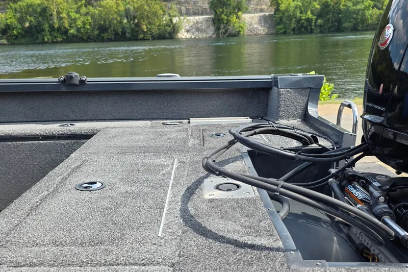 Slide: The Image of 2021 Ranger VS1882 WT boat interior with motor, near a scenic riverbank. - 18