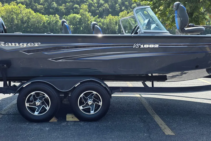 Slide: The Image of 2021 Ranger VS1882 WT boat on trailer, parked in a lot with trees in background. - 39
