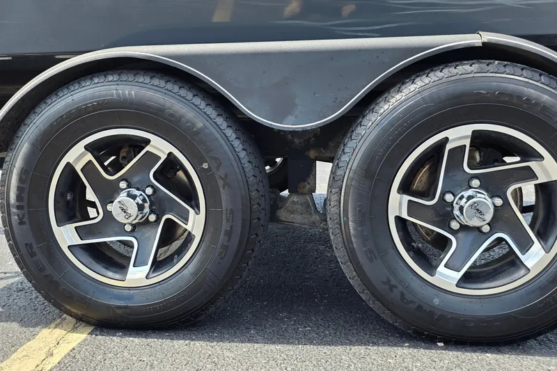 Slide: The Image of 2021 Ranger VS1882 WT trailer wheels on asphalt, featuring black and silver rims. - 23
