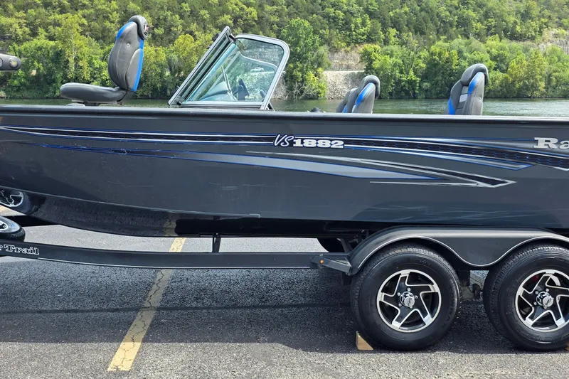 The Image of 2021 Ranger VS1882 WT boat on trailer, parked near lush green landscape. - 6