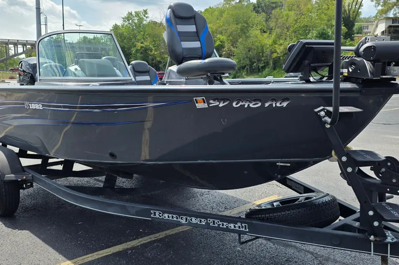 Slide: The Image of 2021 Ranger VS1882 WT boat on trailer, parked outdoors, with blue accents and seating. - 2