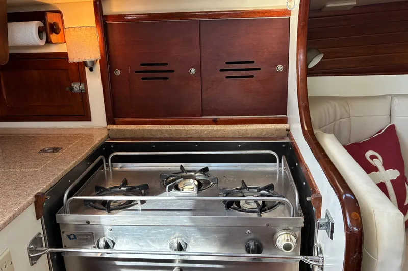 Slide: The Image of Hinckley Bermuda 40 MKIII 1966 yacht interior with a stainless steel stove and wooden cabinetry. - 29