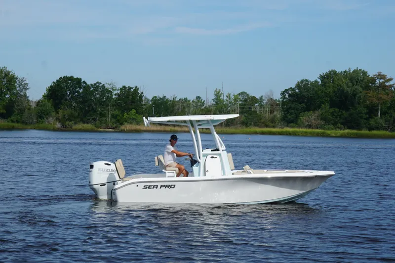 The Image of 2024 Sea Pro 202 Center Console boat on a calm lake with lush greenery. - 1