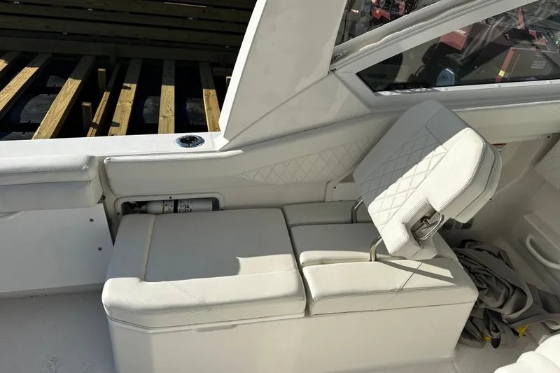 Slide: The Image of 2023 Edgewater 262CX Crossover boat interior with white cushioned seating and storage compartment. - 15