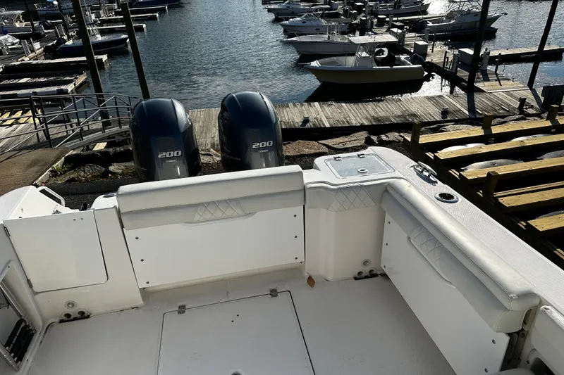 Slide: The Image of 2023 Edgewater 262CX Crossover boat with twin 200 horsepower engines at a marina. - 7