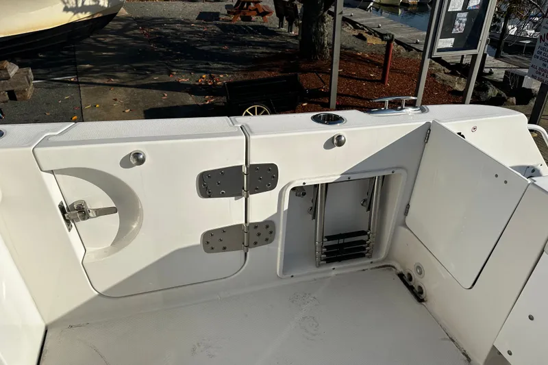 Slide: The Image of 2023 Edgewater 262CX Crossover boat interior with open storage compartments and ladder. - 11