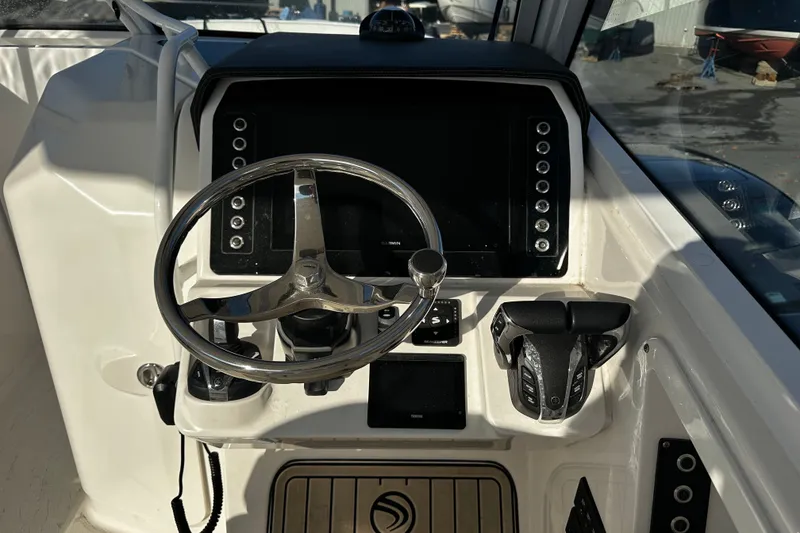 Slide: The Image of 2023 Edgewater 262CX Crossover boat helm with steering wheel and control panel. - 17