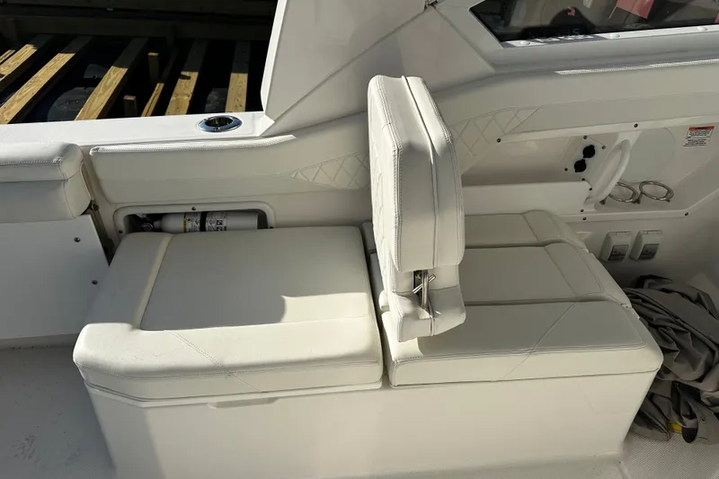 Slide: The Image of 2023 Edgewater 262CX Crossover boat interior with white cushioned seating and storage compartment. - 14