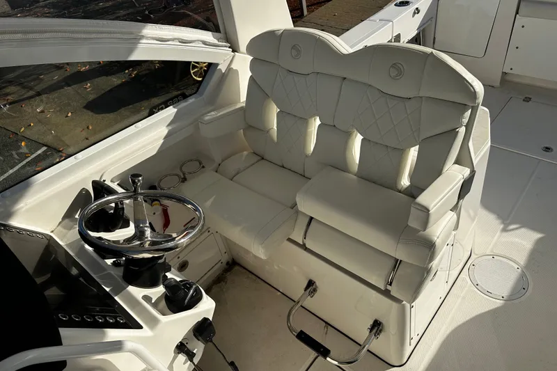 Slide: The Image of Luxurious helm seating on 2023 Edgewater 262CX Crossover boat with steering wheel and controls. - 16