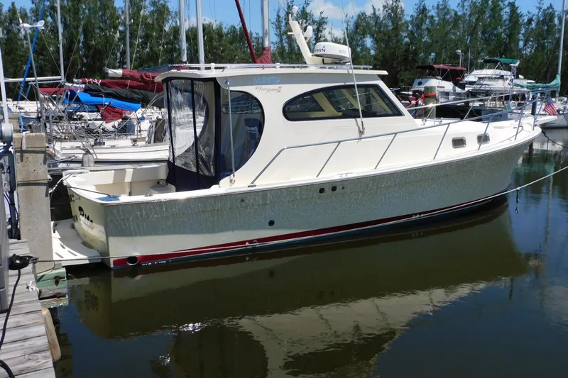 Slide: The Image of 2004 Mainship Pilot 30 Rum Runner docked at marina, surrounded by other boats. - 7