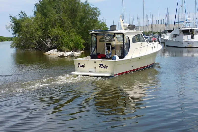 Slide: The Image of 2004 Mainship Pilot 30 Rum Runner cruising in a serene marina setting. - 5