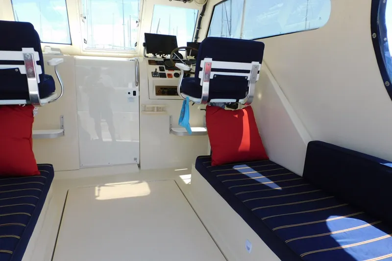 Slide: The Image of 2004 Mainship Pilot 30 Rum Runner interior with navy seating and red cushions. - 23