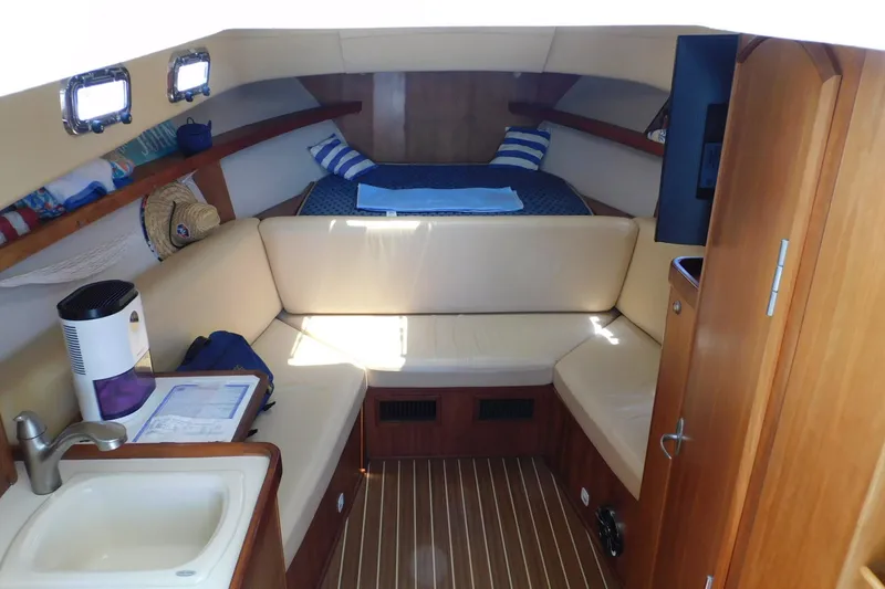 Slide: The Image of 2004 Mainship Pilot 30 Rum Runner cabin interior with seating, bed, and kitchenette. - 25