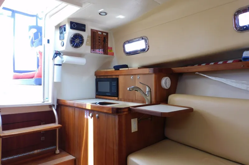 Slide: The Image of Interior of 2004 Mainship Pilot 30 Rum Runner with kitchenette and seating area. - 28