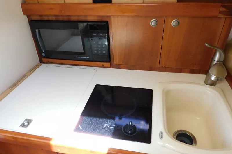 Slide: The Image of 2004 Mainship Pilot 30 Rum Runner galley with microwave, stove, and sink. - 26