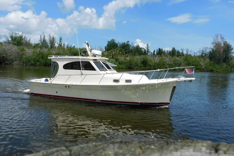 Slide: The Image of 2004 Mainship Pilot 30 Rum Runner cruising on a calm river under a clear blue sky. - 3