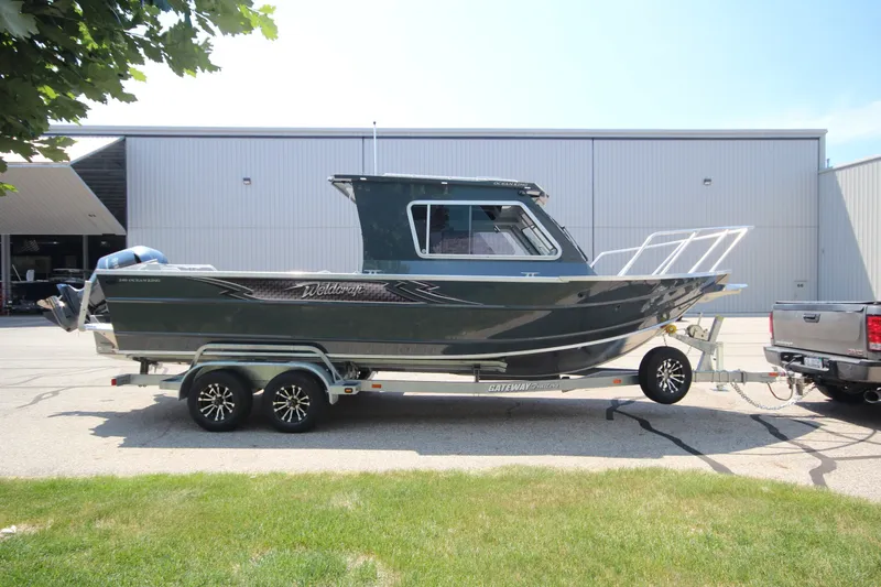 The Image of 2027 Weldcraft 240 Ocean King boat on trailer, parked outdoors near industrial building. - 0